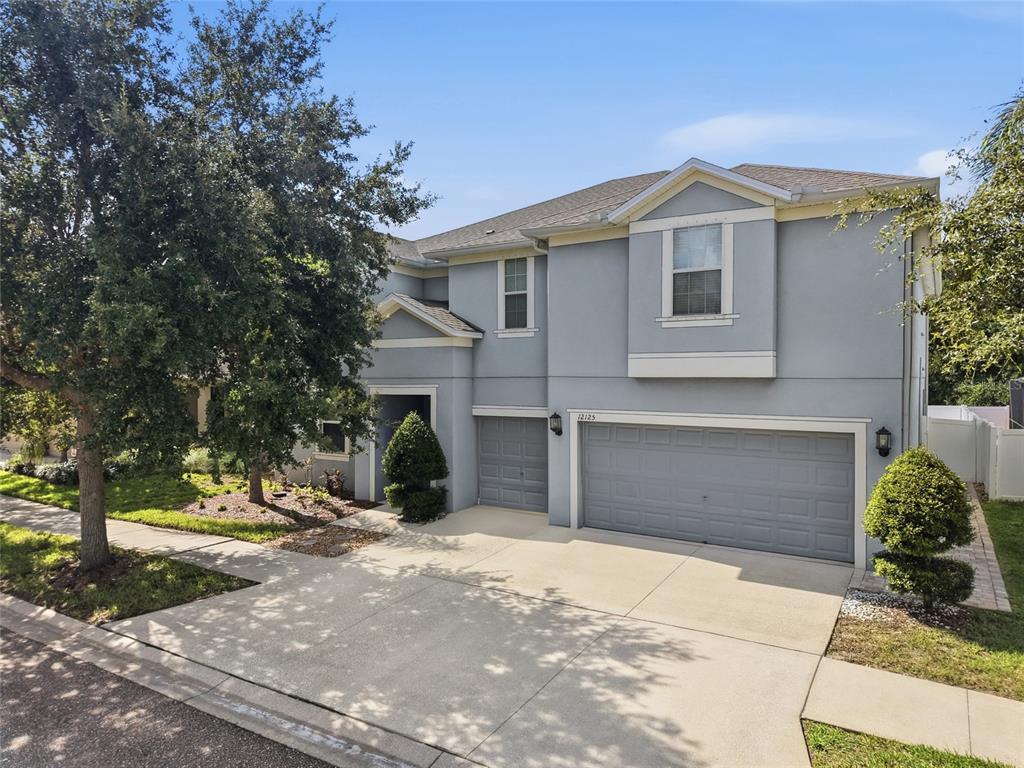 A two-story house with a light blue exterior, a three-car garage, and a concrete driveway — 12125 STREAMBED DRIVE, RIVERVIEW, FL