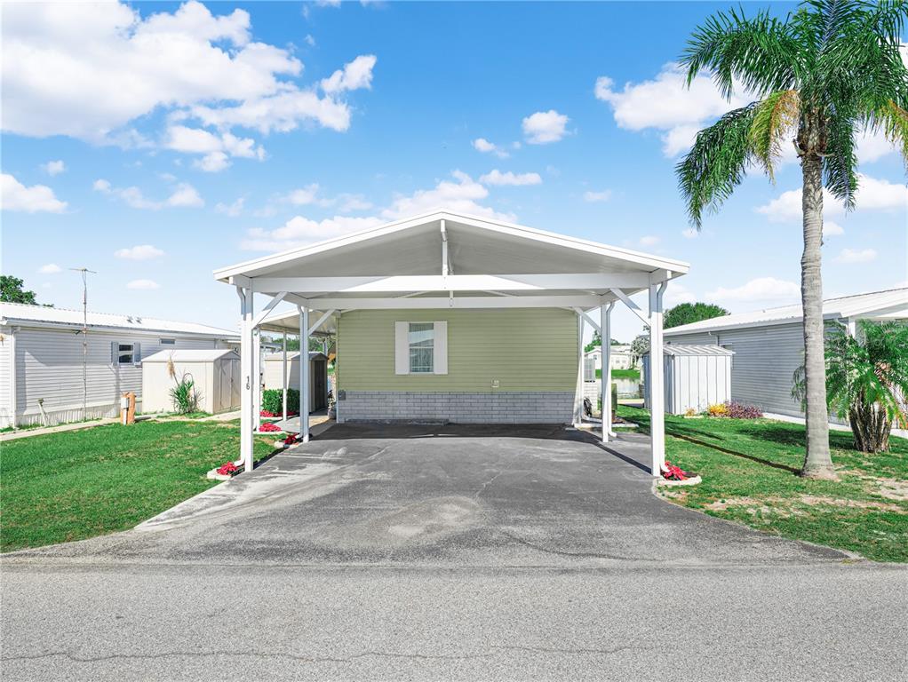 A light green mobile home features a large white carport and a paved driveway — 16 QUEEN OF WATERS STREET, LAKE WALES, FL