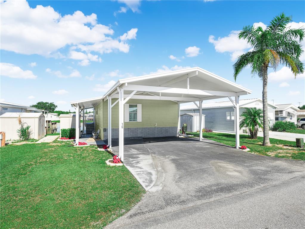 A light green mobile home features a white carport and a paved driveway — 16 QUEEN OF WATERS STREET, LAKE WALES, FL