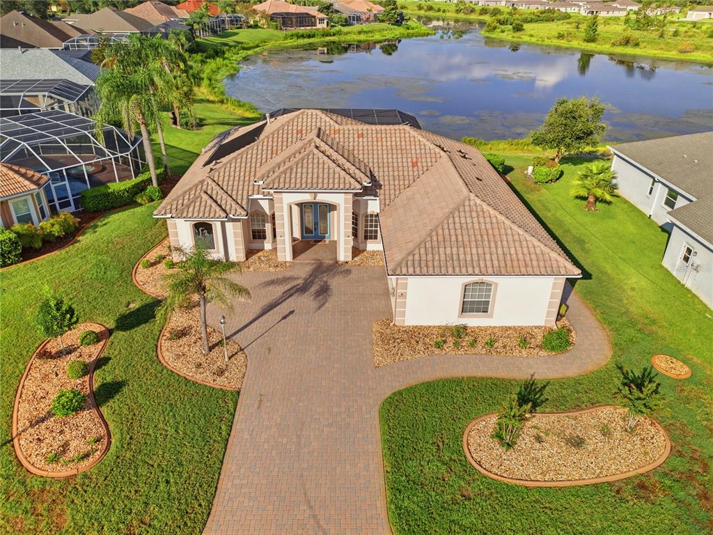 An aerial view shows a single-story house with a tile roof, paver driveway, and lakefront backyard — 9271 WESTSHORE DRIVE, WEEKI WACHEE, FL