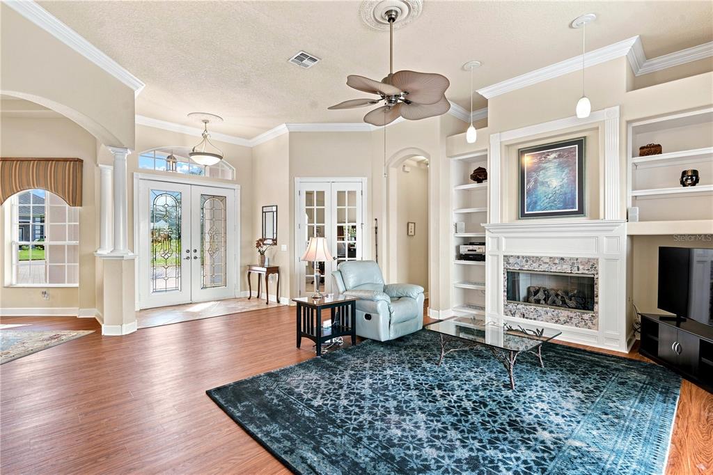 A living room features a fireplace, a ceiling fan, a blue rug, and double entry doors — 9271 WESTSHORE DRIVE, WEEKI WACHEE, FL