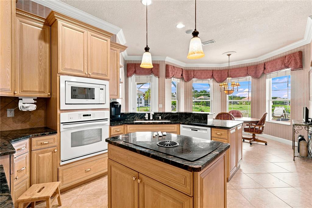 A kitchen with light wood cabinets, dark granite countertops, a center island, and breakfast nook — 9271 WESTSHORE DRIVE, WEEKI WACHEE, FL