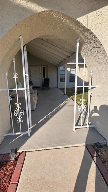 A covered concrete patio features a white wrought iron gate and a seating area — 8089 WOODEN DRIVE, SPRING HILL, FL