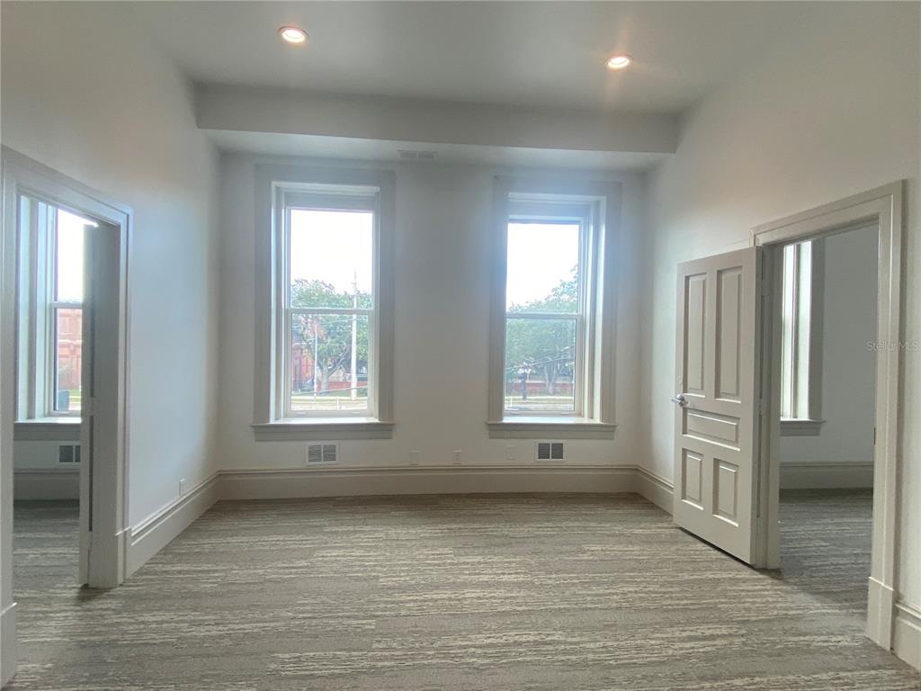 An empty room with two windows, white walls, and gray patterned carpeting — 1718 E 7TH AVENUE UNIT 201-C & E, TAMPA, FL