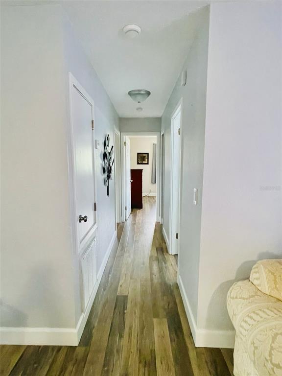 A hallway with light-colored walls and wood-look flooring leads to a doorway at the end — 1643 SAXON BOULEVARD, DELTONA, FL