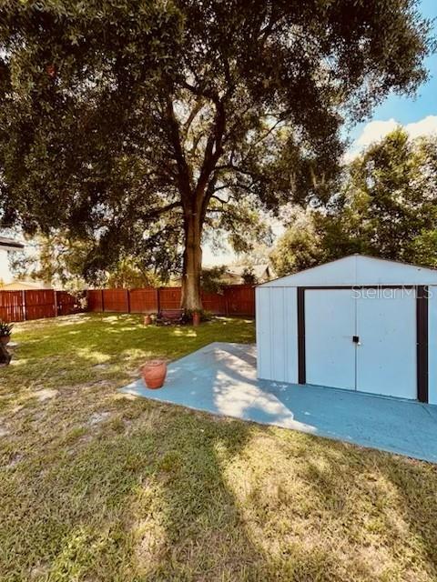 A large tree stands in a backyard with a shed on a concrete pad — 1643 SAXON BOULEVARD, DELTONA, FL