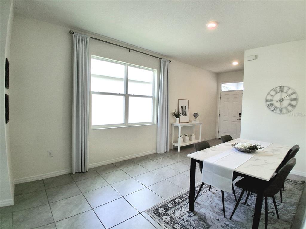 A dining area with a marble-topped table leads into a kitchen and living space — 8072 PENROSE PLACE, WILDWOOD, FL