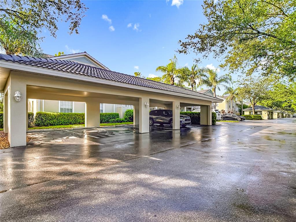 A covered parking area features three numbered concrete parking spaces and a view of landscaping — 25735 LAKE AMELIA WAY UNIT 103, BONITA SPRINGS, FL