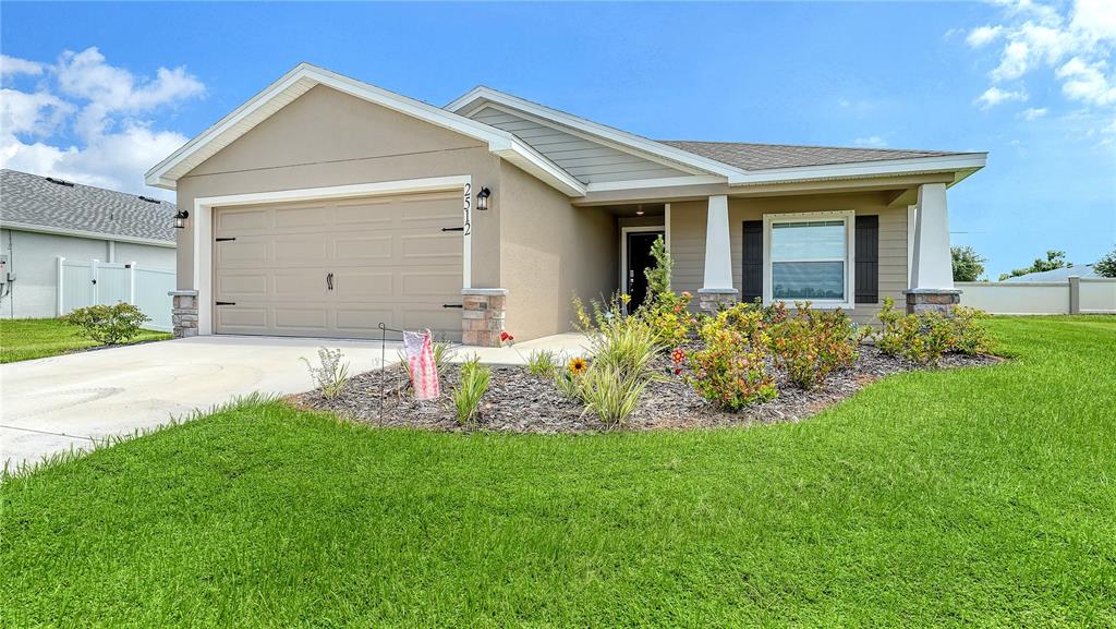 A single-story house with a tan exterior, a two-car garage, and a landscaped front yard — 2512 58TH CIRCLE E, PALMETTO, FL