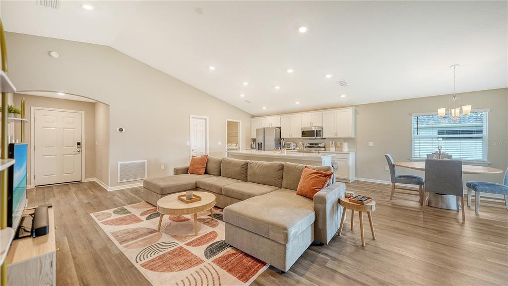 An open-concept living room and kitchen feature a large sectional sofa, dining area, and island — 2512 58TH CIRCLE E, PALMETTO, FL
