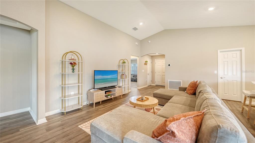 A living room features a sectional sofa, a television on a console, and two shelves — 2512 58TH CIRCLE E, PALMETTO, FL