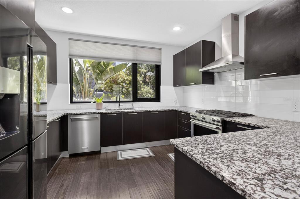 A kitchen features dark cabinetry, speckled granite countertops, stainless steel appliances, and a large window — 2511 N GRADY AVENUE UNIT 78, TAMPA, FL