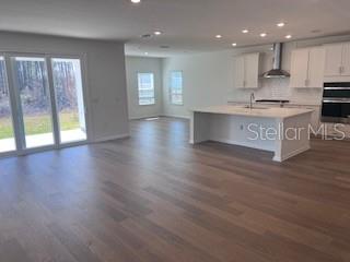 An open-concept kitchen and living area features light wood flooring and a large center island — 298 BROOK FOREST DRIVE, ST AUGUSTINE, FL