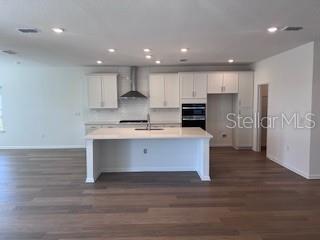 A modern kitchen features white cabinets, a central island, and light wood-look flooring — 298 BROOK FOREST DRIVE, ST AUGUSTINE, FL