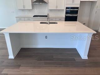 A kitchen island with a white countertop and sink sits before white cabinets and appliances — 298 BROOK FOREST DRIVE, ST AUGUSTINE, FL