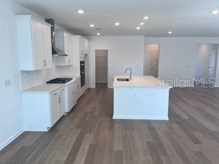 A modern kitchen features white cabinetry, a central island, and light wood-look flooring — 298 BROOK FOREST DRIVE, ST AUGUSTINE, FL