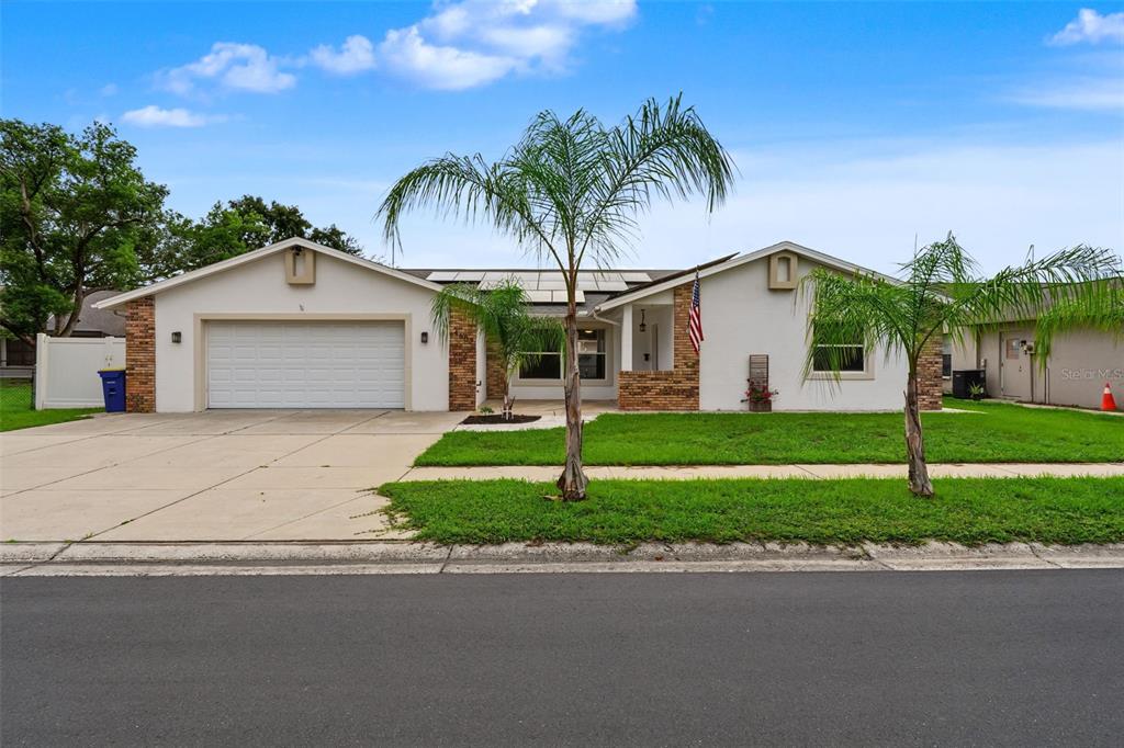 An aerial view of a single-story house with a garage, solar panels, and palm trees — 4607 SAWGRASS BOULEVARD, NEW PORT RICHEY, FL