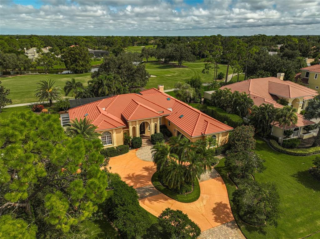 An aerial view of a single-story house with a red tile roof and circular driveway — 909 MACEWEN DRIVE, OSPREY, FL