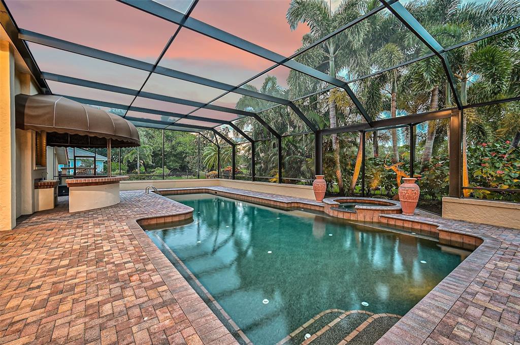A screened-in pool area with a brick patio, a built-in bar, and a hot tub — 909 MACEWEN DRIVE, OSPREY, FL