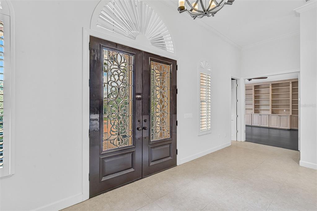 A bright entryway features double doors with decorative glass panels and a semi-circular transom window — 909 MACEWEN DRIVE, OSPREY, FL