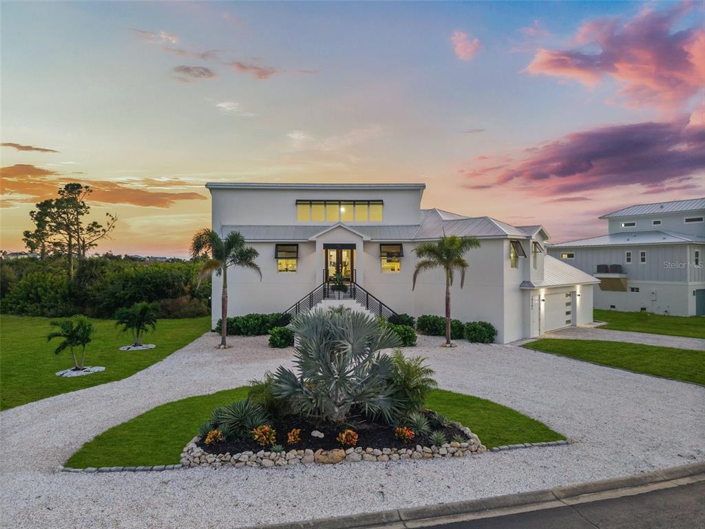 A modern two-story house with a gravel driveway, palm trees, and a landscaped garden — 10101 EAGLE PRESERVE DRIVE, ENGLEWOOD, FL