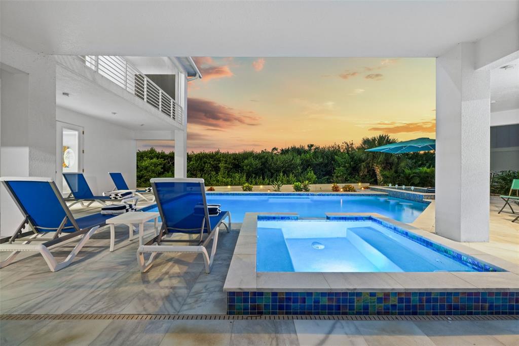 A covered patio features a swimming pool, a hot tub, and lounge chairs at sunset — 10101 EAGLE PRESERVE DRIVE, ENGLEWOOD, FL