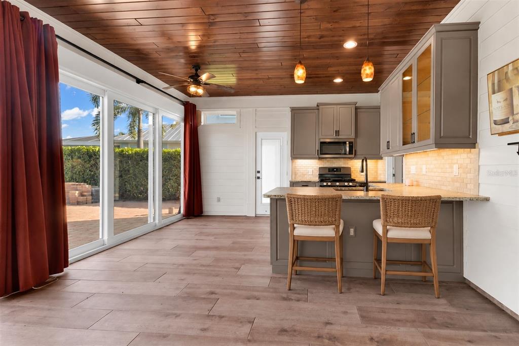 A kitchen and living area with a wood-paneled ceiling, tile floors, and sliding glass doors — 8306 SW SAND CRANE LOT 87 CIRCLE, ARCADIA, FL