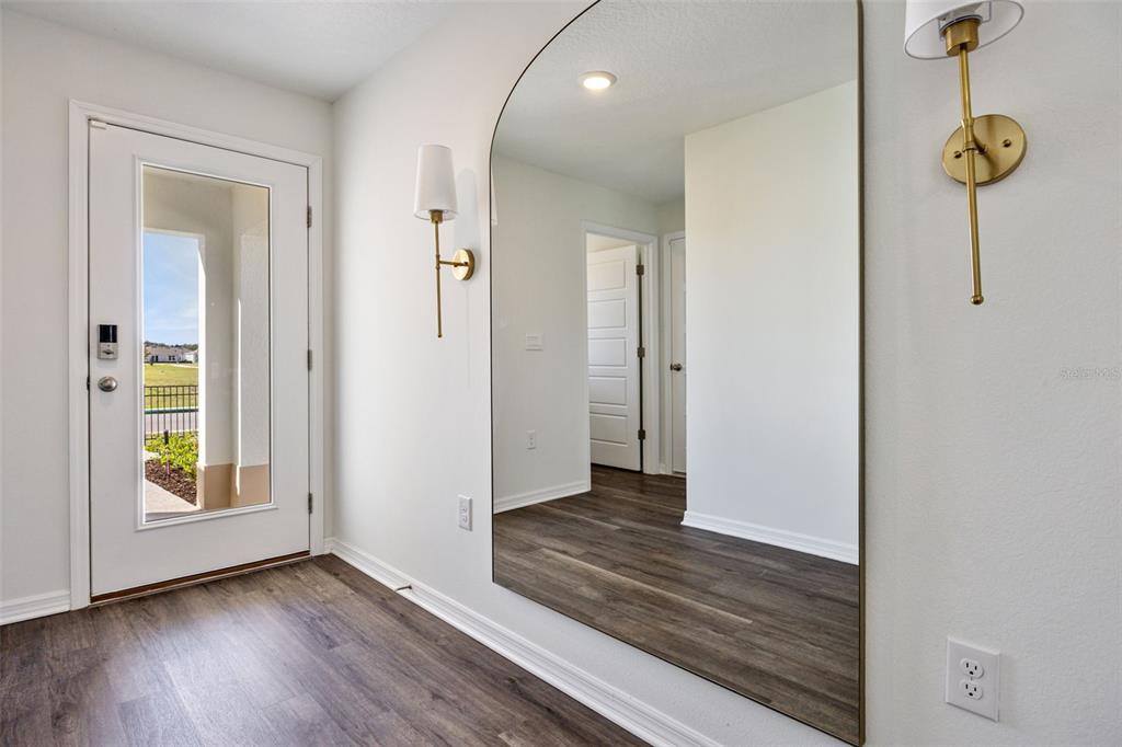 An entryway features wood-look flooring, a large arched mirror, and two gold wall sconces — 1770 GRANDIOSE DRIVE, LAKE HAMILTON, FL