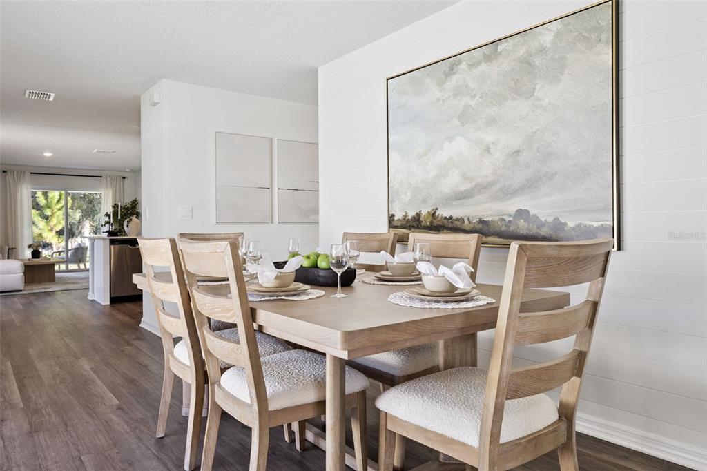A dining room features a wooden table with upholstered chairs against a white shiplap wall — 1770 GRANDIOSE DRIVE, LAKE HAMILTON, FL