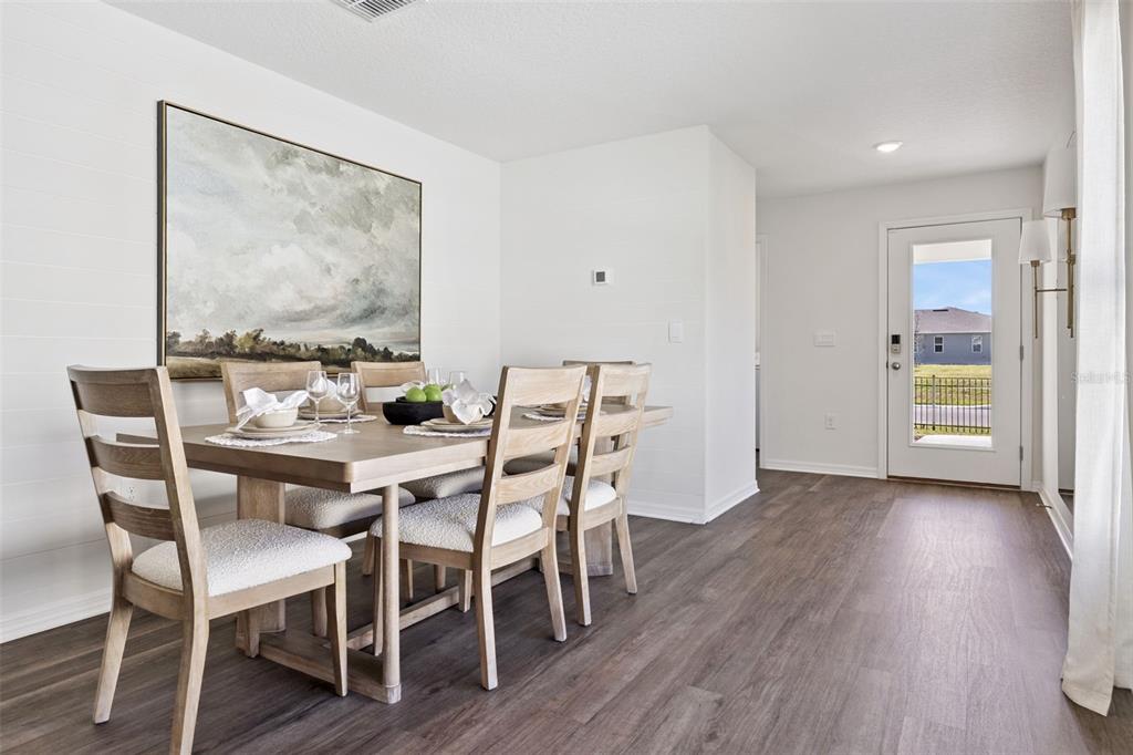 A dining room with a wooden table, six chairs, wall art, and a glass-paneled exterior door — 1770 GRANDIOSE DRIVE, LAKE HAMILTON, FL