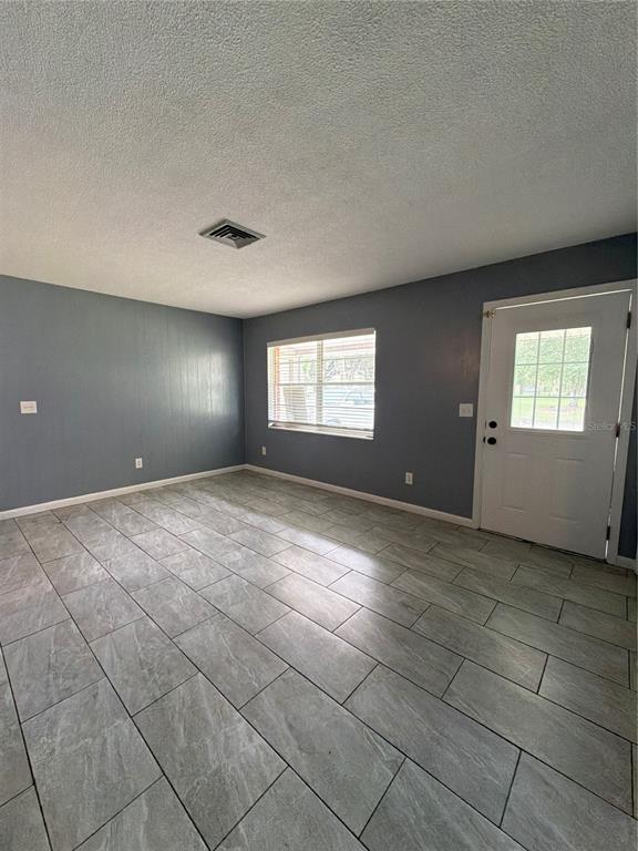A kitchen features white cabinets, speckled countertops, stainless steel appliances, and a black refrigerator — 1655 N FLORAL AVENUE, BARTOW, FL