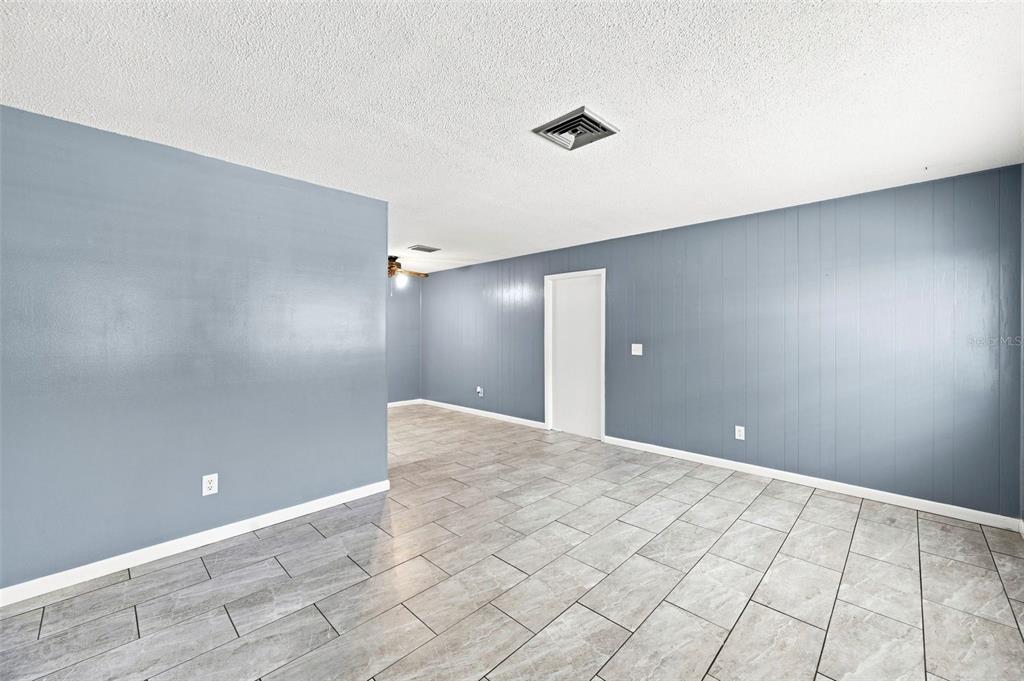 An interior view of a room with gray paneled walls and light-colored tile flooring — 1655 N FLORAL AVENUE, BARTOW, FL