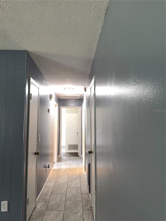 An interior view of a room with gray paneled walls and light-colored tile flooring — 1655 N FLORAL AVENUE, BARTOW, FL