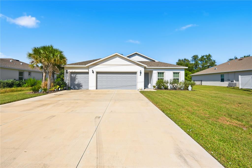 A single-story house with a three-car garage and a concrete driveway under a blue sky — 403 SEASONS DRIVE, PUNTA GORDA, FL