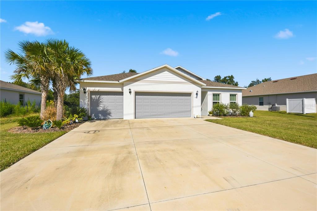 A single-story house with a three-car garage, a concrete driveway, and a palm tree — 403 SEASONS DRIVE, PUNTA GORDA, FL
