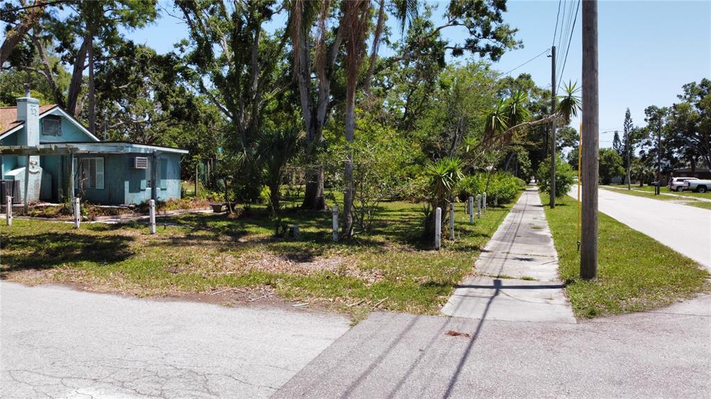 A vacant lot with a sidewalk and a neighboring house under a clear blue sky — 5680 77TH AVENUE N, PINELLAS PARK, FL