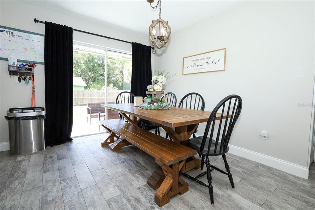 A dining room features a wooden table with a bench and chairs under a chandelier — 738 E 11TH AVENUE, MOUNT DORA, FL