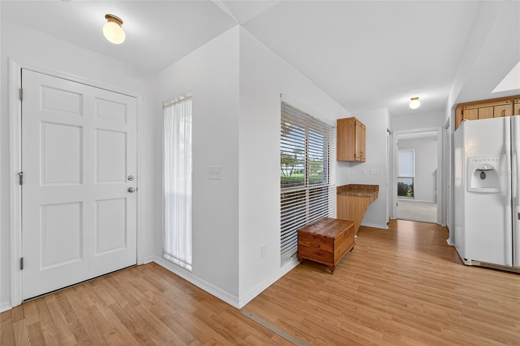 An entryway with wood-look flooring, a white front door, and a view into a kitchen — 236 MEADOW LAKE DRIVE, EDGEWATER, FL