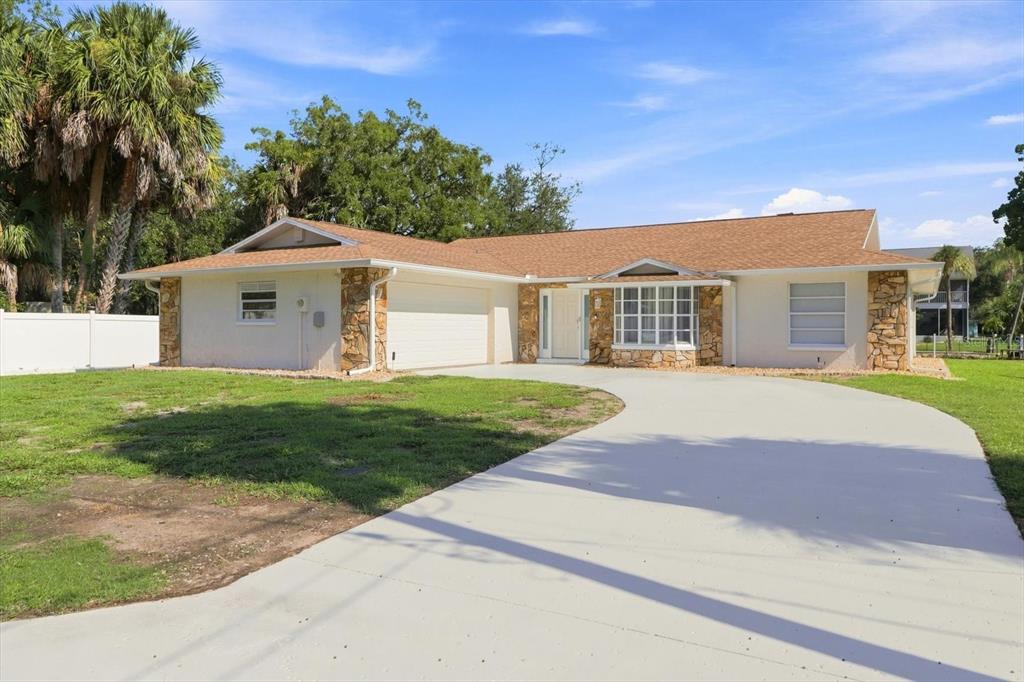 A single-story house with a tan roof, stone accents, and a large concrete driveway — 11291 W CORAL CT, CRYSTAL RIVER, FL