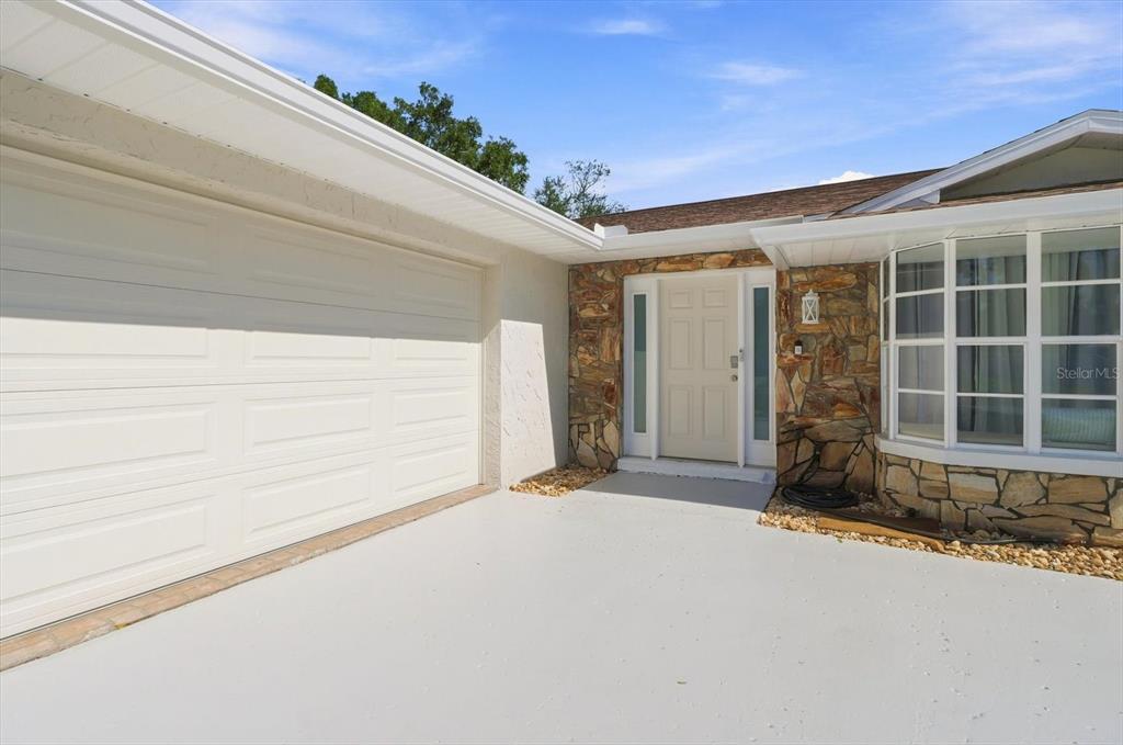 A single-story house with a light-colored exterior, stone accents, and a brown shingled roof — 11291 W CORAL CT, CRYSTAL RIVER, FL