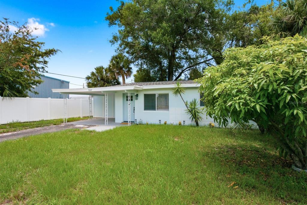 A single-story house with a light blue exterior, a carport, and a white vinyl fence — 5307 BERKLEY ROAD, NEW PORT RICHEY, FL