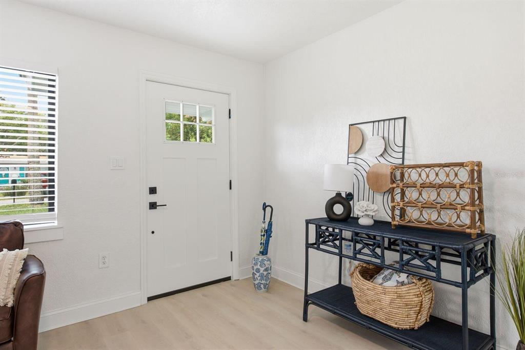 An entryway features a white front door, light wood flooring, and a dark blue console table — 5307 BERKLEY ROAD, NEW PORT RICHEY, FL