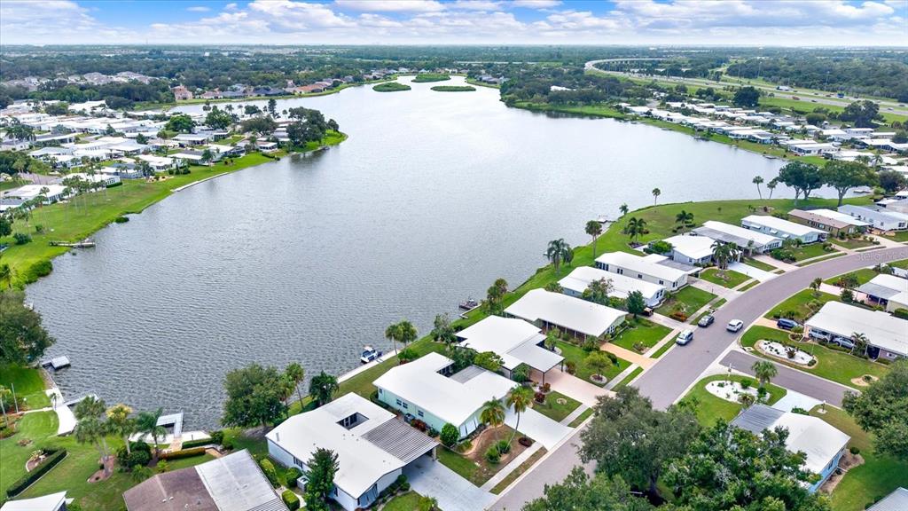 An aerial view shows a lake surrounded by residential homes and a nearby highway — 8479 IMPERIAL CIRCLE, PALMETTO, FL