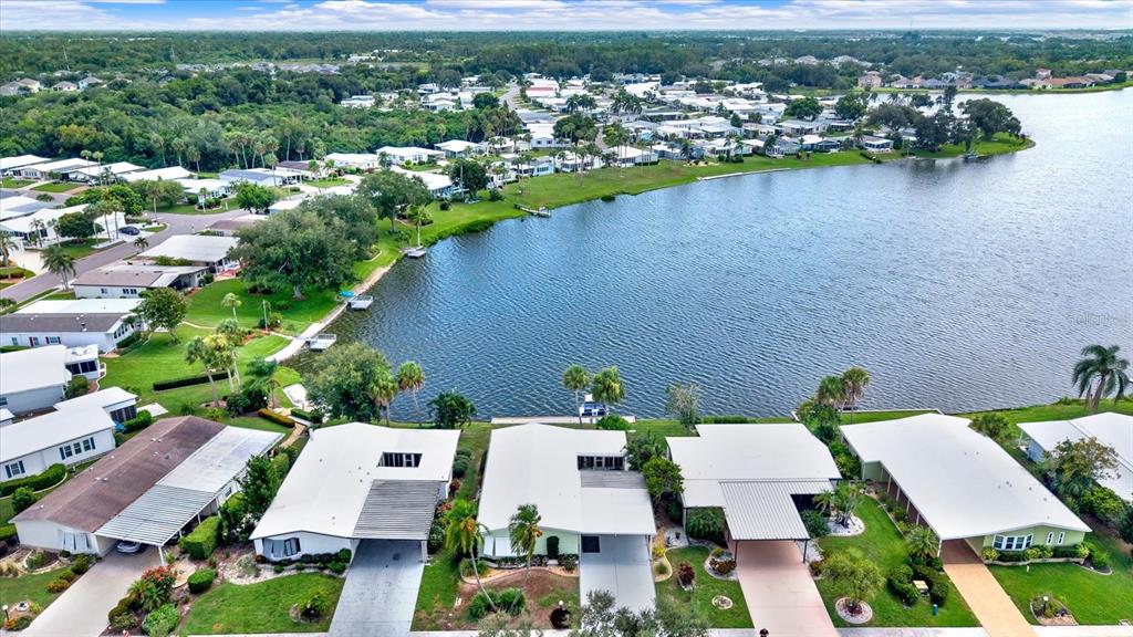 An aerial view shows a residential neighborhood with white houses situated along a lake — 8479 IMPERIAL CIRCLE, PALMETTO, FL