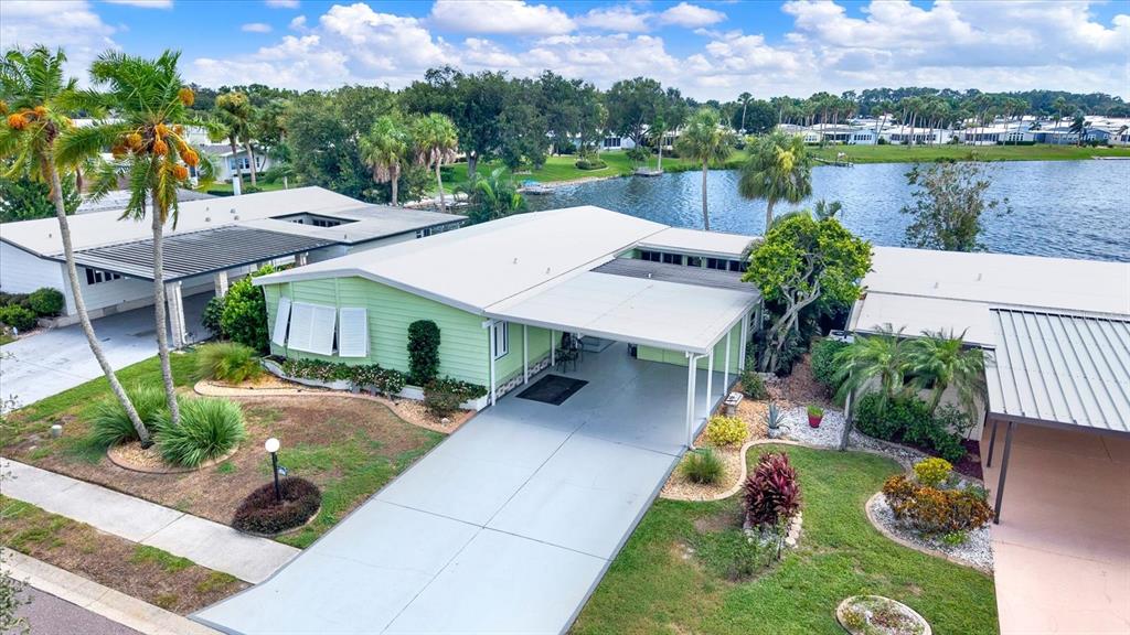 An aerial view shows a light green manufactured home with a carport and a lake — 8479 IMPERIAL CIRCLE, PALMETTO, FL