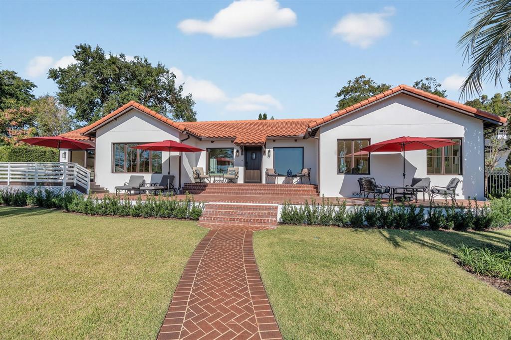 A white house with a red tile roof features a large lawn and palm trees — 631 LAKE CATHERINE DRIVE, MAITLAND, FL