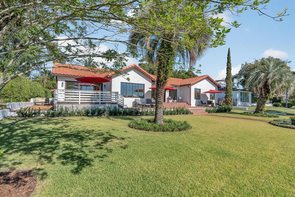 A white house with a red tile roof features a patio with outdoor furniture — 631 LAKE CATHERINE DRIVE, MAITLAND, FL