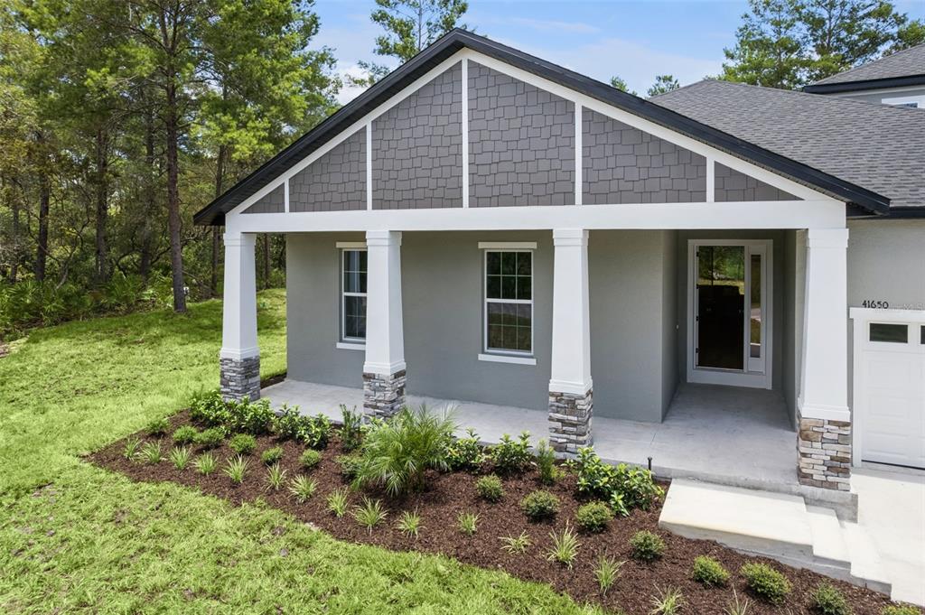 A gray house exterior features a covered porch with white columns and stone bases — 41650 LIGUSTRUM STREET, EUSTIS, FL