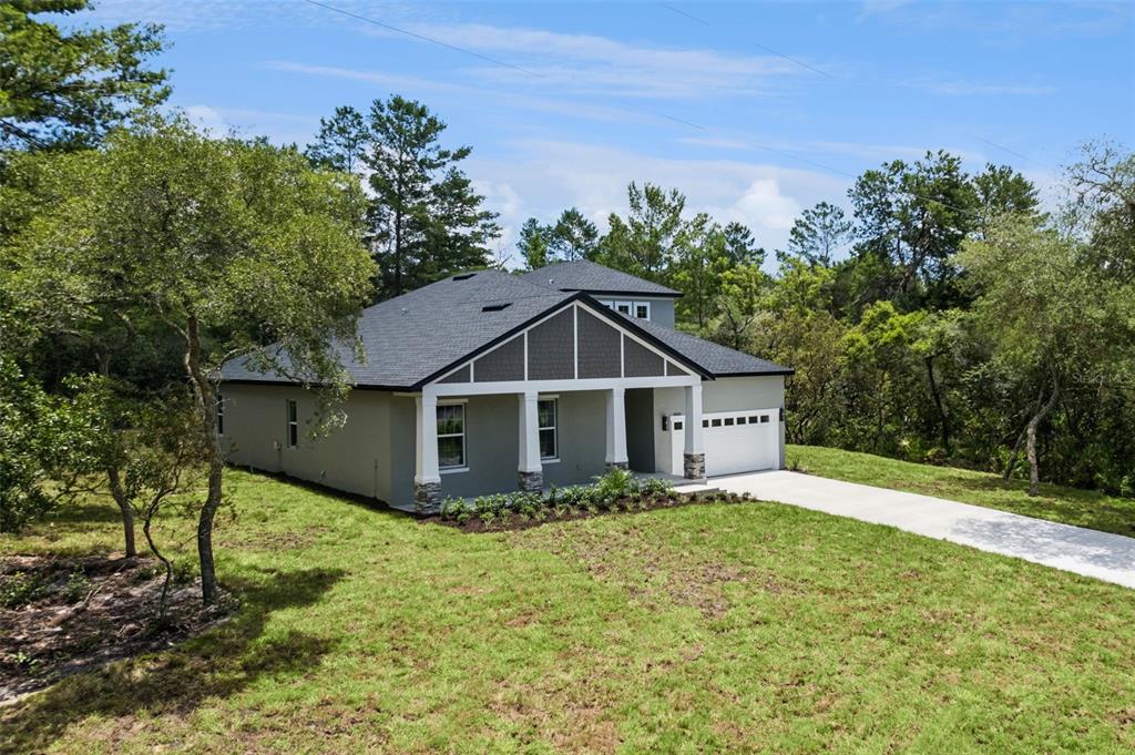 An exterior view of a single-story house with a gray facade, dark roof, and garage — 41650 LIGUSTRUM STREET, EUSTIS, FL