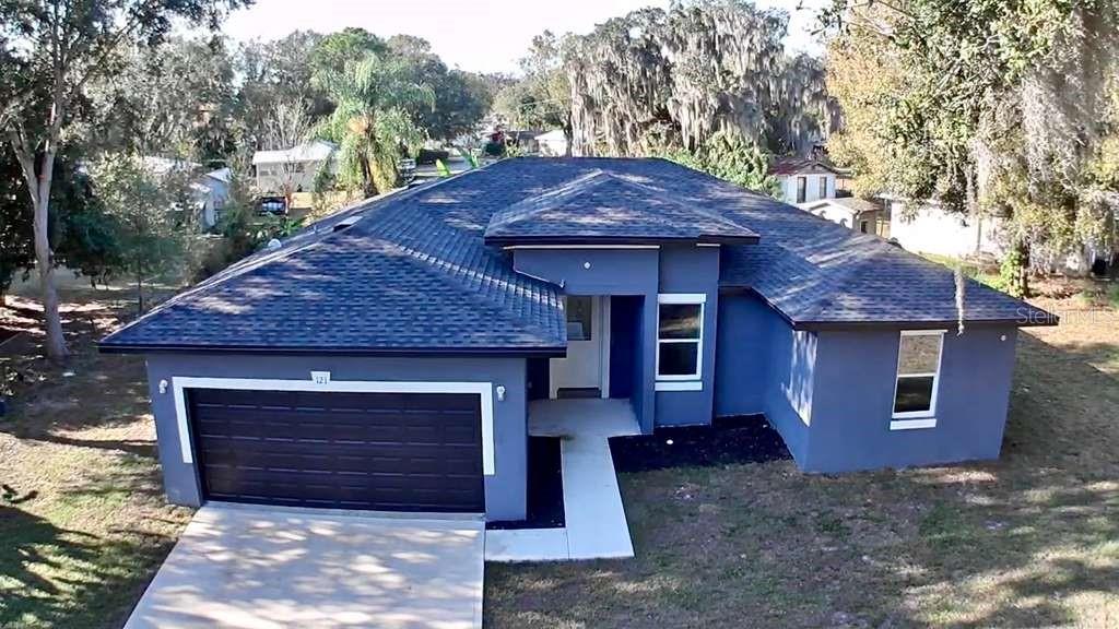 An aerial view of a blue single-story house with a dark roof and two-car garage — 121 ARGYLE AVENUE, FROSTPROOF, FL